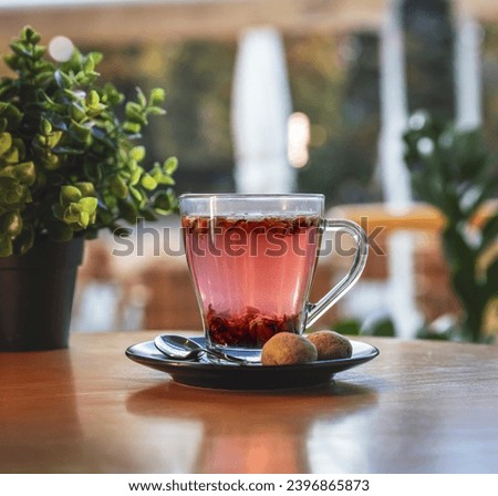 Glass cup of tea on a black saucer served with two small cookies  Royalty-Free Stock Photo #2396865873