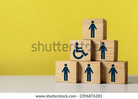 Inclusive workplace culture. Pyramid of wooden cubes with human icons and one with international symbol of access on yellow background