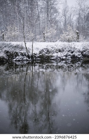 Amazing winter rural landscape with a frozen small pond. Silhouettes of trees on the river bank