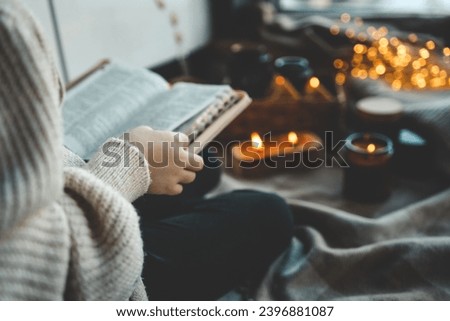 Girl with a Bible in her hands in a cozy home interior, concept of prayer and worship.