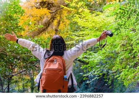 Happy woman raiseก open arms with camera in natural park, lifestyle and healthy confidence relax woman concept.