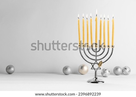 Hanukkah celebration. Menorah with burning candles and holiday ornaments on white wooden table, space for text