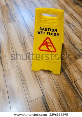 Warning signs in yellow on wooden flooring in public spaces, signs that read "Caution Wet Floor" are posted. Steps to guarantee that guests passing by don't trip and fall.