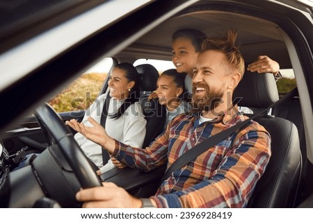 Portrait of happy laughing smiling family of four with children riding in modern car traveling by automobile together enjoying vacation or road trip on weekend. Family travel concept. Royalty-Free Stock Photo #2396928419