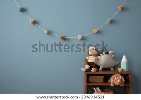 Warm and cozy kid room interior with blue wall, modern white sideboard, plush lama, monkey, dog, toys, colorful garland on wall, pink basket, crayons and personal accessories. Home decor. Template.