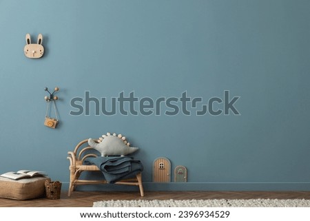 Cozy composition of blue living room interior with copy space, gray desk, green chair, plush dog, braided rug, colorful garland on wall, wooden wall, and personal accessories. Home decor. Template.