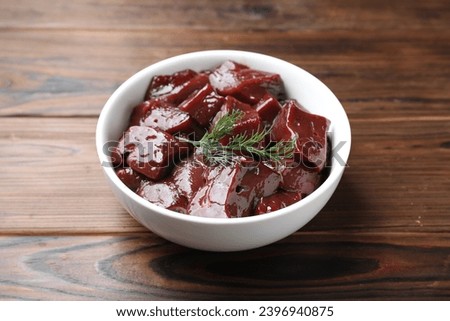 Cut raw beef liver with dill on wooden table, closeup Royalty-Free Stock Photo #2396940875