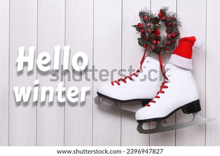 Hello winter. Pair of ice skates and Christmas wreath hanging on white wooden wall