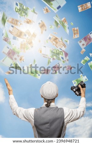 Successful young photographer with camera under dollars money rain, , demonstrating that his dedication and skill have translated into significant financial rewards