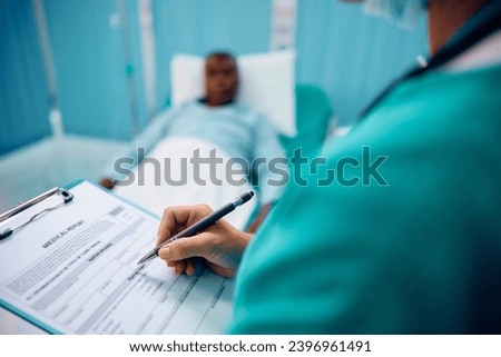 Close up of nurse taking notes in patient's medical record during his recovery in the hospital. 