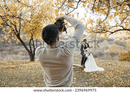 Professional male wedding photographer taking pictures of the bride and groom in nature