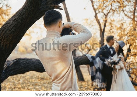 Professional wedding photographer taking pictures of the bride and groom on the wedding day. in autumn