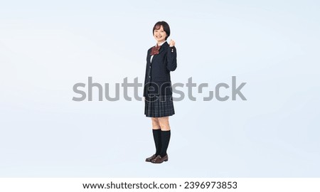 Asian girl wearing school uniform showing fist pump. High school student. Wide angle visual for banners or advertisements. Royalty-Free Stock Photo #2396973853