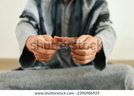 Close up hand holding money for donation or giving zakat. Islamic concept  Royalty-Free Stock Photo #2396986929