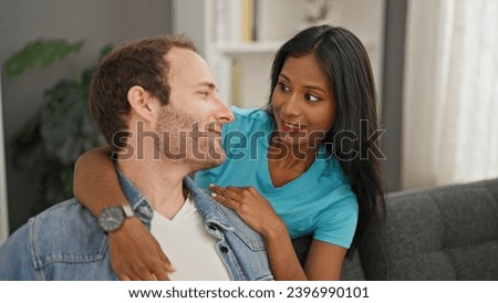 Beautiful couple hugging each other sitting on sofa speaking at home