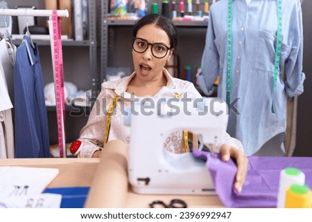 Young arab woman dressmaker designer working at atelier confuse and wondering about question. uncertain with doubt, thinking with hand on head. pensive concept.  Royalty-Free Stock Photo #2396992947