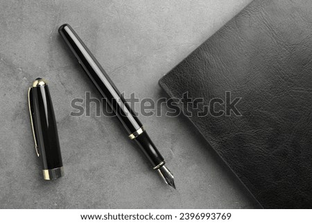 Stylish fountain pen, cap and leather notebook on light grey textured table, flat lay Royalty-Free Stock Photo #2396993769