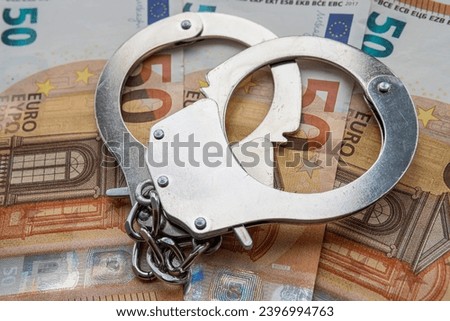 metal handcuffs against the background of the cash currency euro. The concept of bribery or criminal money. Royalty-Free Stock Photo #2396994763