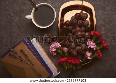 Female flat lay breakfast with grapes, cup of coffee, books and flowers on the golden tray.