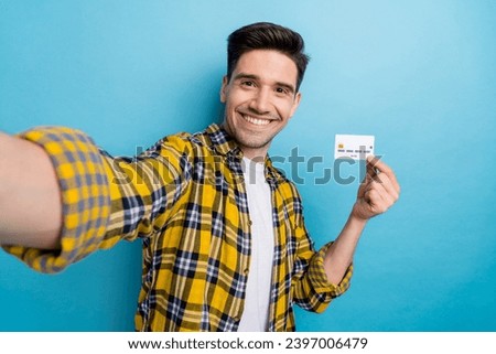 Photo of positive good mood guy wear yellow checkered shirt recording video vlog rising bank card isolated blue color background