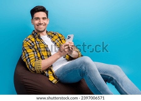 Photo of handsome man brunet hair businessman using smartphone sitting brown pouf relaxing at terrace isolated on blue color background Royalty-Free Stock Photo #2397006571