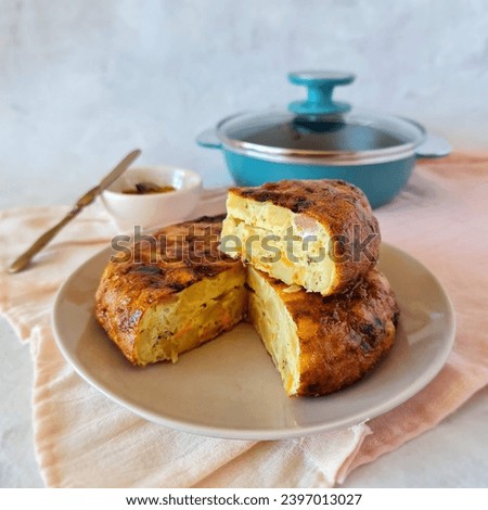 
potato omelette on white plate white background pink tablecloth turquoise frying pan Royalty-Free Stock Photo #2397013027