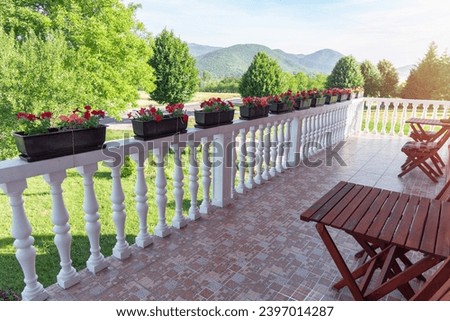 Outdoor terrace of a house with chairs and flowers.