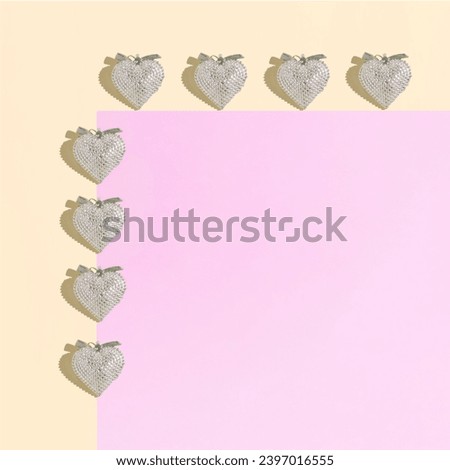 A repetitive pattern made of silver hearts against pink and powder peach background. Minimal concept of love and friendship. Flat lay. Valentine’s card pattern.