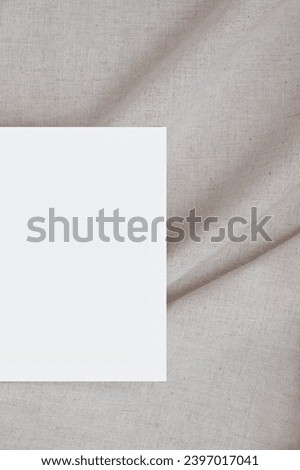 Blank paper card mockup on soft blurry crumpled linen neutral beige fabric background with folds and natural shadows, elegant wedding invitation or business card branding template.