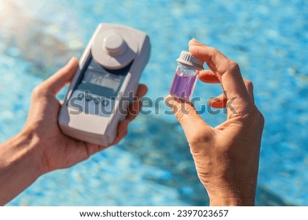 person testing swimming pool water with a digital test device and a small sample container