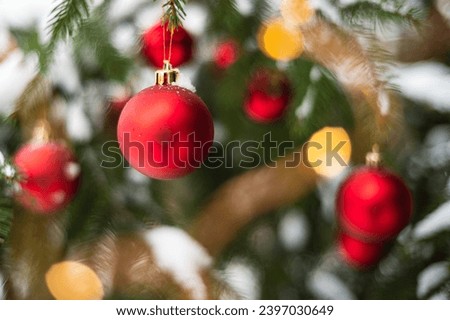 Red baubles on a snow-covered Christmas tree outdoors