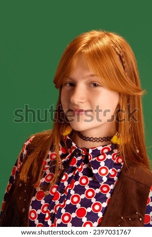 Close-up portrait of red haired cheerful, smiling young cowgirl, teenager looking at camera against green studio background. Concept of human emotions, retro fashion, western style, wild-west. Royalty-Free Stock Photo #2397031767