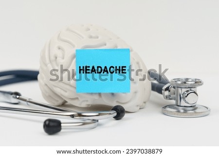 Medical concept. On a white surface next to the stethoscope lies a brain on which a sticker with the inscription - Headache