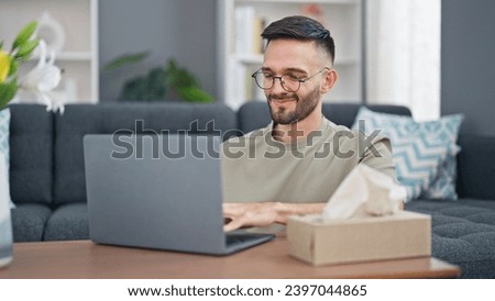 Young hispanic man using laptop sitting on floor smiling at home