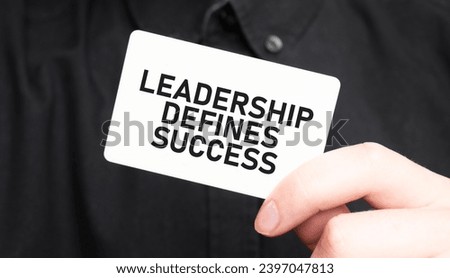 Businessman holding a card with text LEADERSHIP DEFINES SUCCESS, business concept