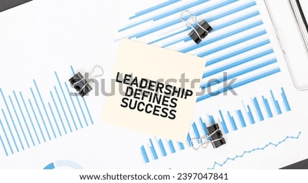Yellow sticky notes with text LEADERSHIP DEFINES SUCCESS on the white office desk. Business concept.