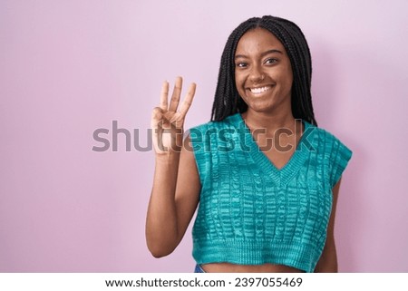 Young african american with braids standing over pink background showing and pointing up with fingers number three while smiling confident and happy. 