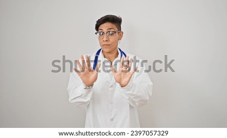 Young beautiful hispanic woman doctor standing with serious expression doing calm gesture over isolated white background