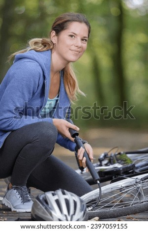 woman inflating bicycle tyre with pump Royalty-Free Stock Photo #2397059155