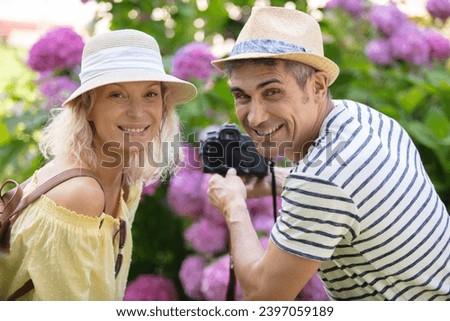 photographer and wife taking photo of blossoming bush