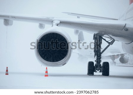 Traffic at airport during heavy snowfall. Snowflakes against jet engine and taxiing airplane at airport taxiway during frosty winter day. Extreme weather in transportation.
 Royalty-Free Stock Photo #2397062785