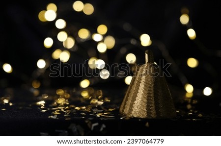 Golden bell on a bokeh background. Black photo. Copy space.