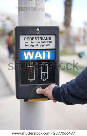 young man pressing on a crosswalk sign 