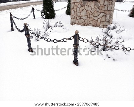 A metal chain link fence around a stone plinth in winter. A thick layer of snow covered everything around.