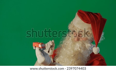 Portrait of Santa Claus painting a car with a gift on a green background.