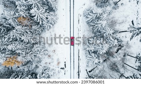 Aerial view of a red car in the snow near the small town of Lubomierz in Lower Silesia, Poland. The shots were recorded in winter.
