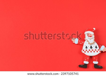 Toy Cheerful Santa Claus shows on red background. Smiling cartoon old man in suit, saint nicholas, Happy New Year celebration, Christmas greeting card. Holiday Christmas, birthday