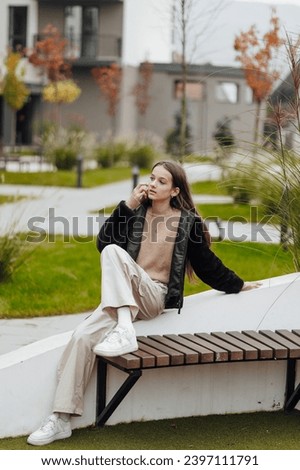 Vertical photo. Beautiful carefree young teenage girl in casual clothes. Portrait of a beautiful girl against the background of nature with a blurred background.