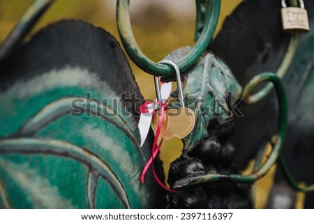 A heart-shaped steel padlock hangs on a fence with a ribbon, closed by the bride and groom. Wedding photography, symbol of love, Ukrainian traditions, copy space.