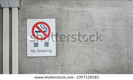 No smoking sign in Japanese and English text with icon banner on metal wall. Sign and symbol object photo.